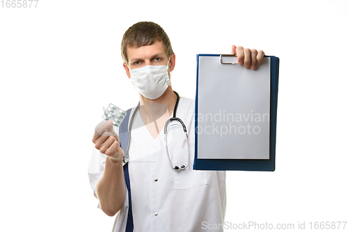 Image of The doctor shows a tablet with a white sheet of paper in the frame, holds medicines in the other hand, focusing on the tablet