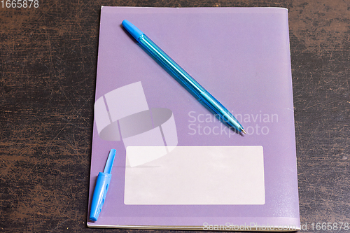 Image of On the old table is a notebook and a pen with an open cap