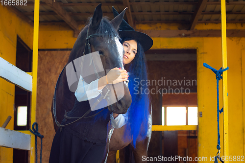 Image of A girl dressed as a witch hugs a horse and looks thoughtfully into the distance