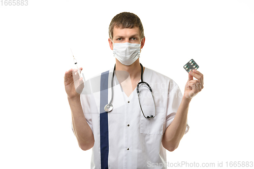 Image of Male doctor holding a syringe with medicine in one hand and pills in the other hand, isolated on white background