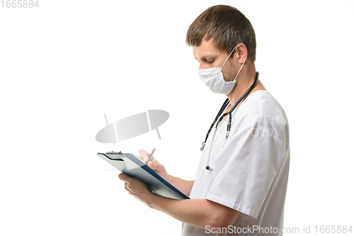 Image of Male doctor writes in a clipboard with a ballpoint pen