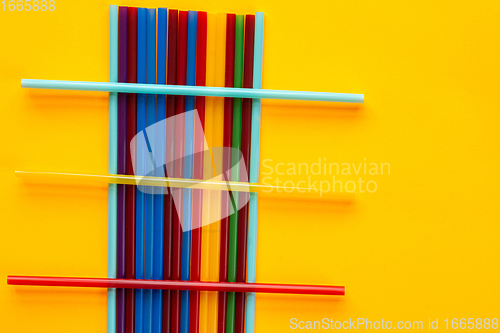 Image of On a yellow background are multi-colored cocktail tubes, on a heap of vertical tubes are three horizontal