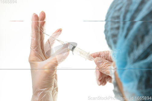 Image of The doctor picks up the drug from the ampoule with a syringe, close-up