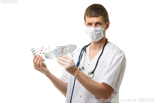 Image of The doctor holds a variety of medications in his hands and joyfully looks into the frame