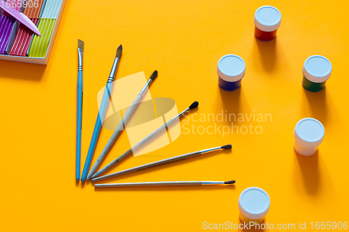 Image of Brushes, gouache and plasticine are laid out on an orange table