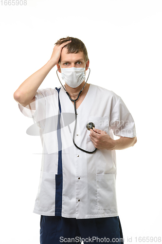 Image of Doctor in a mask listens to his heart, with the other hand holds his sore head, isolated on white background