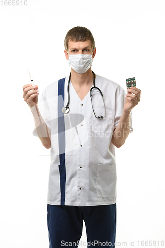 Image of Portrait of a doctor holding a syringe with medicine in one hand and pills in the other hand, isolated on white background