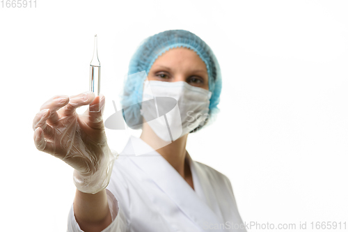 Image of Girl doctor in a medical mask holds an ampoule with medicine in her hand