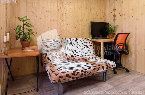 Image of Interior of a country house room, next to the sofa there is a computer table, on the other side there is a coffee table