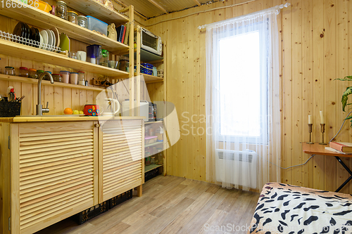 Image of The interior of a small kitchen in a country cottage, the walls are decorated with wooden clapboard