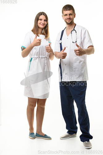 Image of Doctor and nurse show thumbs up gesture with two hands and look happily into the frame