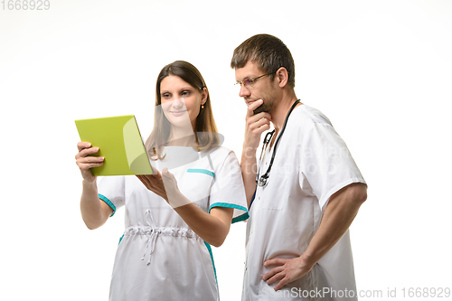 Image of The nurse shows the test results in a tablet computer, the doctor looks thoughtfully at the screen