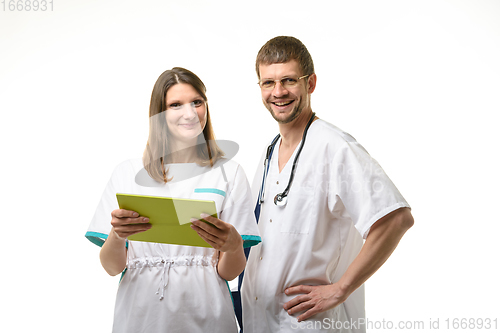 Image of The doctor and the nurse discuss the patient\'s tests and look happily into the frame