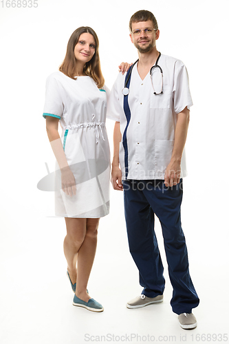 Image of the nurse put her hand on the doctor\'s shoulder, both happily look into the frame, full length