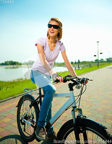Image of Young woman is sitting on her bicycle