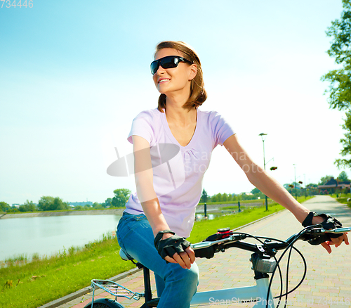Image of Young woman is sitting on her bicycle