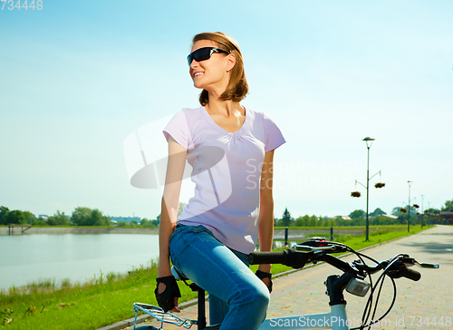 Image of Young woman is sitting on her bicycle