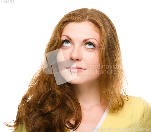 Image of Young happy woman is looking up and smile