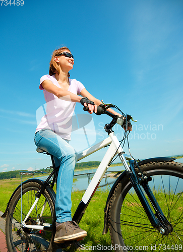 Image of Young woman is sitting on her bicycle
