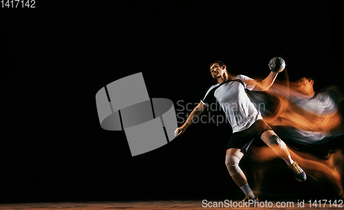 Image of Young handball player against dark studio background in mixed light