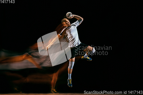 Image of Young handball player against dark studio background in mixed light