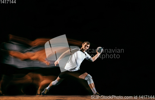 Image of Young handball player against dark studio background in mixed light