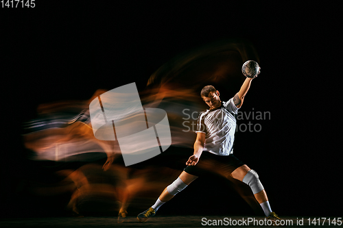 Image of Young handball player against dark studio background in mixed light