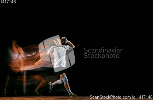 Image of Young handball player against dark studio background in mixed light