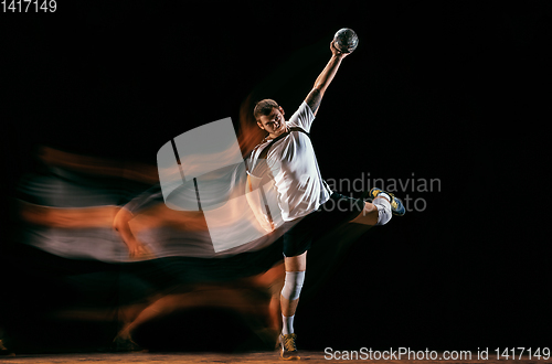 Image of Young handball player against dark studio background in mixed light