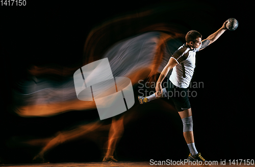 Image of Young handball player against dark studio background in mixed light