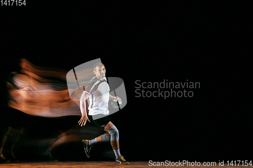 Image of Young handball player against dark studio background in mixed light