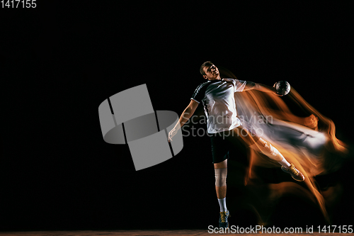 Image of Young handball player against dark studio background in mixed light