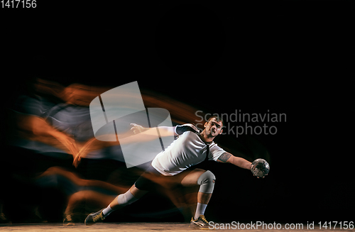 Image of Young handball player against dark studio background in mixed light