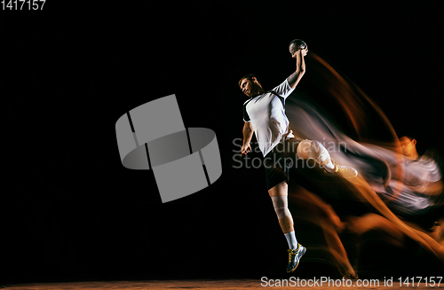 Image of Young handball player against dark studio background in mixed light