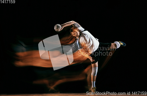 Image of Young handball player against dark studio background in mixed light