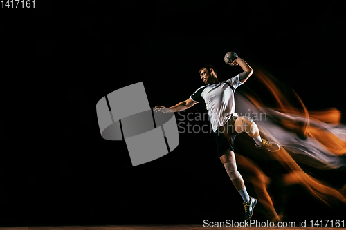 Image of Young handball player against dark studio background in mixed light