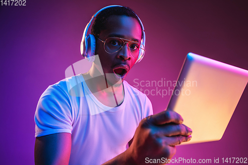 Image of Young african-american man\'s listening to music in neon light