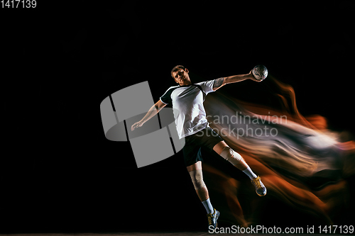 Image of Young handball player against dark studio background in mixed light