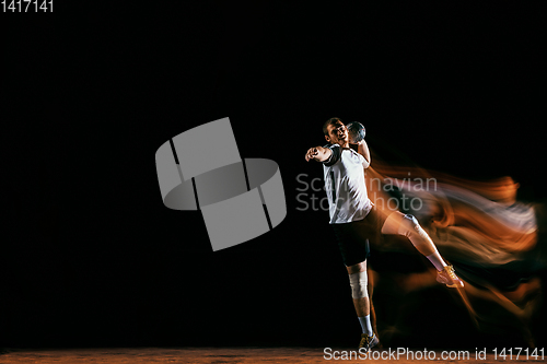 Image of Young handball player against dark studio background in mixed light