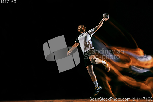 Image of Young handball player against dark studio background in mixed light