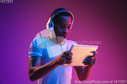 Image of Young african-american man\'s listening to music in neon light