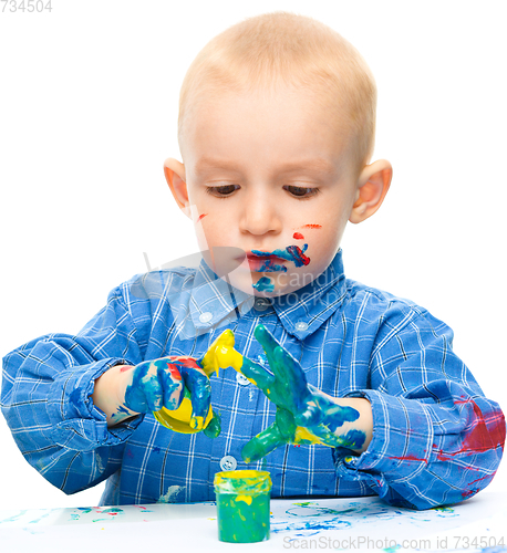 Image of Little boy is playing with paints