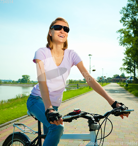 Image of Young woman is sitting on her bicycle