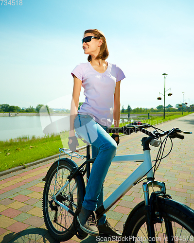 Image of Young woman is sitting on her bicycle