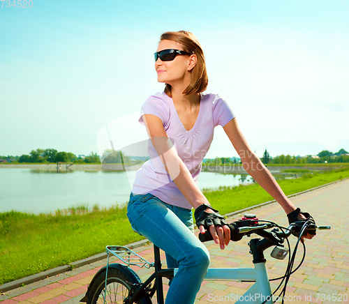 Image of Young woman is sitting on her bicycle