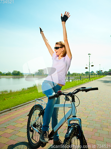 Image of Young woman is sitting on her bicycle