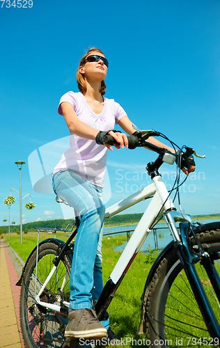 Image of Young woman is sitting on her bicycle