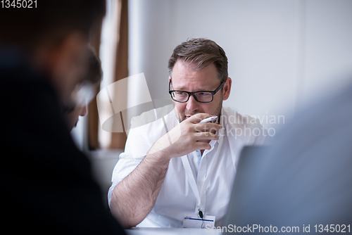 Image of Business man writing notes while working on laptop