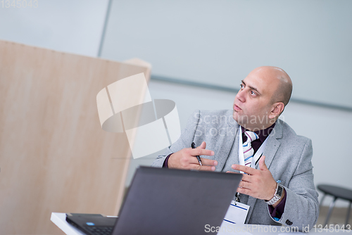 Image of Business man writing notes while working on laptop