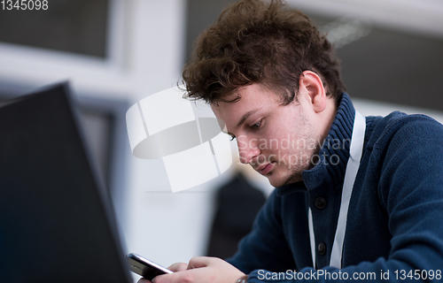 Image of Young casual businessman using smartphone